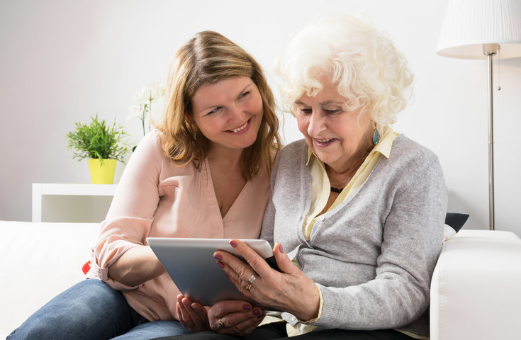 family member showing her grandma a care home on a ipad