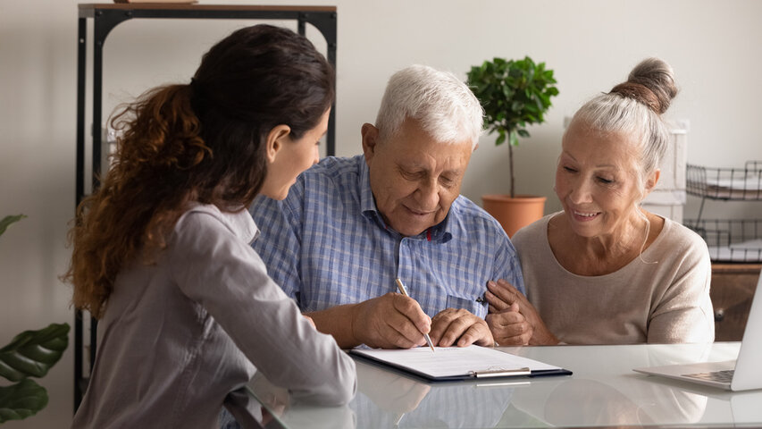 older man and daughter looking at paperwork at a care home and signing an agreement