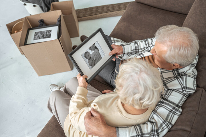 older couple looking through photo albums whilst packing away for a move from home to care home